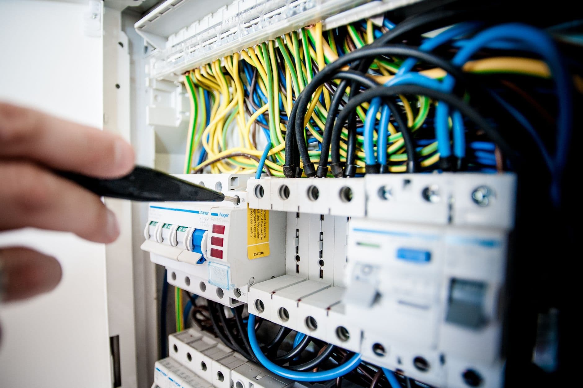An electrician working inside an open circuit breaker panel