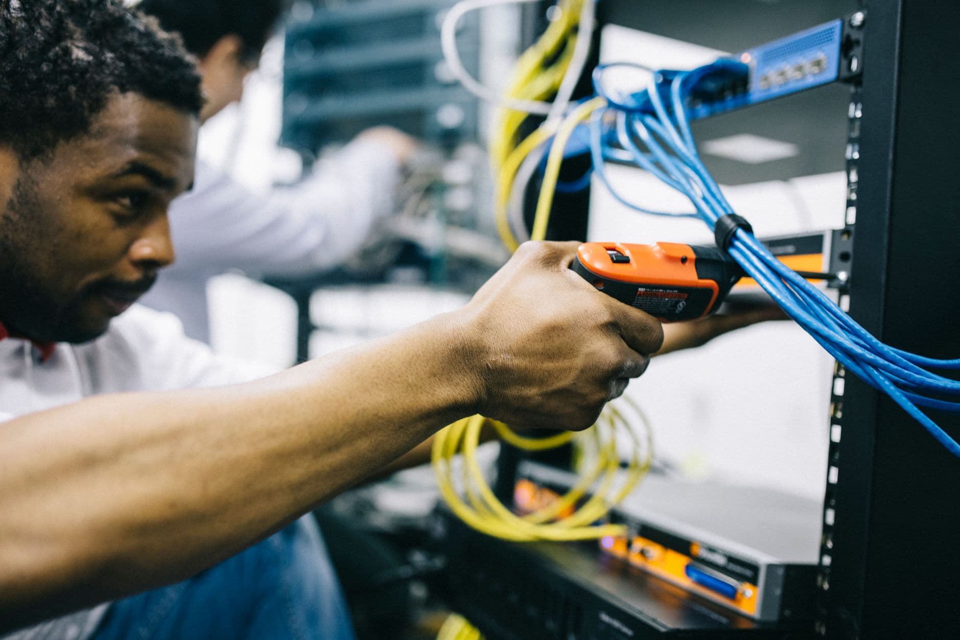 An IT technician securing network cables in a server rack